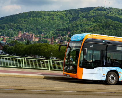 Ein rnv-Bus des Typs H2-eCitaro in Heidelberg vor dem Panorama mit dem Heidelberger Schloss.