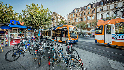 rnv-Verkaufsstelle am Heidelberger Bismarckplatz, zwei Straßenbahnen im Hintergrund