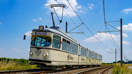 Die Event-Bahn "RHB-1020" des Typs DÜWAG auf der Strecke vor blauem Himmel mit ein paar Wölkchen.
