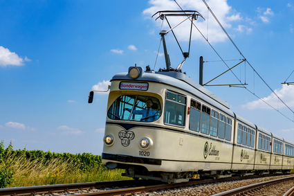Die Event-Bahn "RHB-1020" des Typs DÜWAG auf der Strecke vor blauem Himmel mit ein paar Wölkchen.