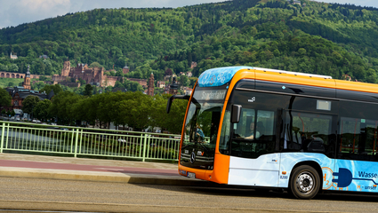 Ein rnv-Bus des Typs H2-eCitaro in Heidelberg vor dem Panorama mit dem Heidelberger Schloss.