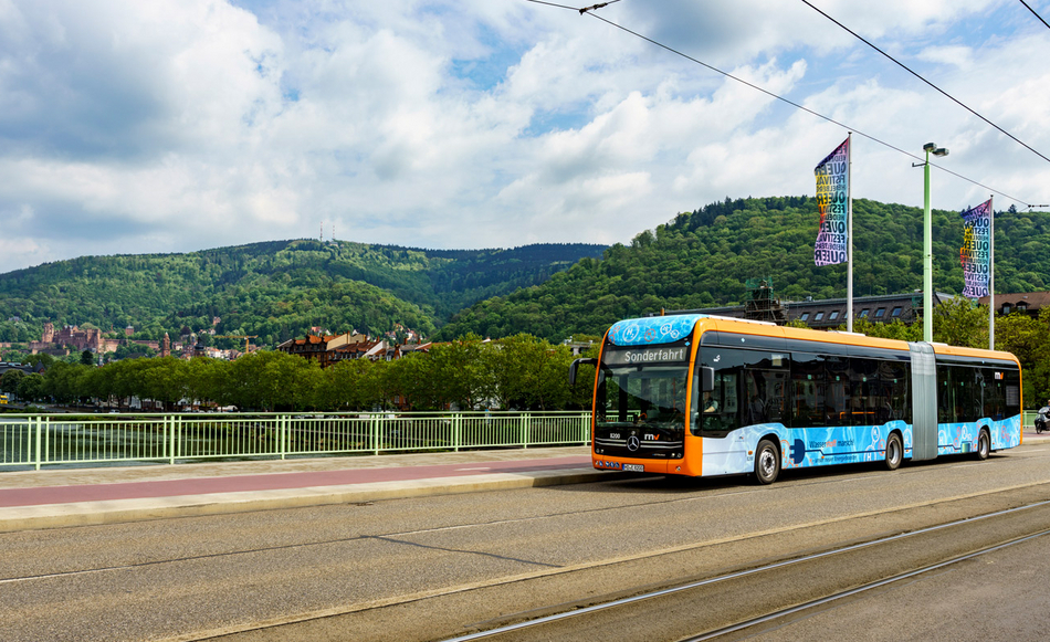 Ein rnv-Bus des Typs H2-eCitaro in Heidelberg vor dem Panorama mit dem Heidelberger Schloss.